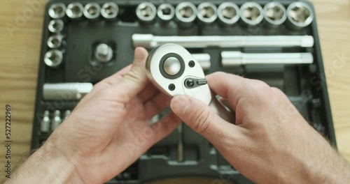 Demonstration of the work of the ratchet keys from the first person. The man switches the mode to unscrew and tighten on the socket wrench. photo