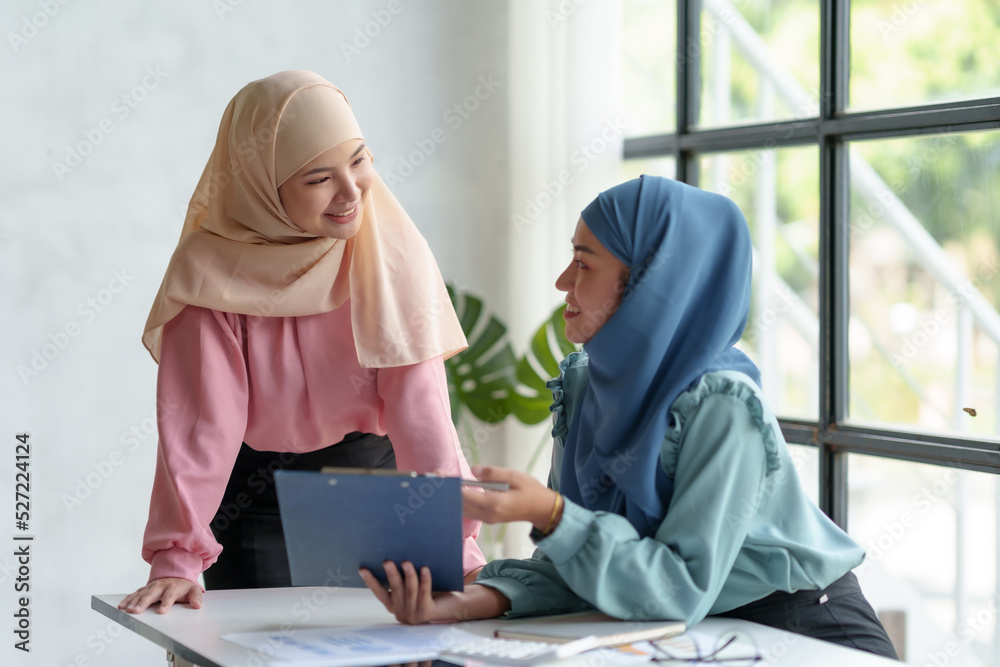 Team work process Two Muslim business women pointing at a laptop computer and discussing document and ideas at a meeting. Team work process Two Muslim business women pointing at a laptop computer and discussing document and ideas at a meeting.