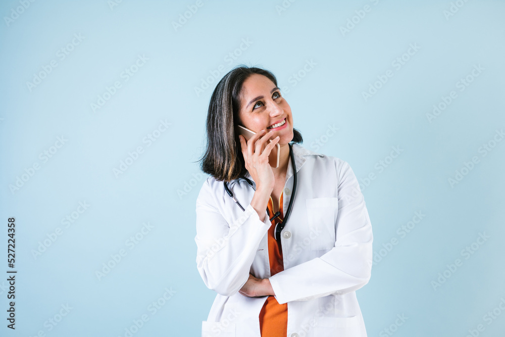 hispanic doctor woman portrait with copy space and holding a mobile phone over blue background laughing in Mexico Latin America hispanic doctor woman portrait with copy space and holding a mobile phone over blue background laughing in Mexico Latin America