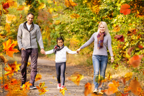 family walking in an autumn park with fallen fall leaves