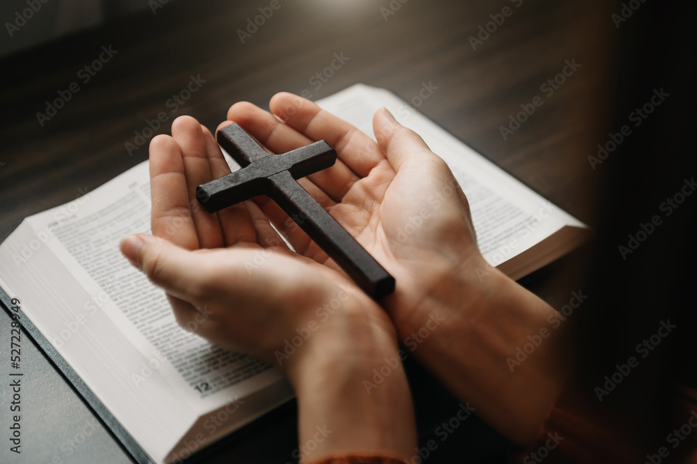 Woman sitting and studying the scriptures.The  wooden cross in the hands. Christian education concepts The Holy Scriptures open and pray to God.