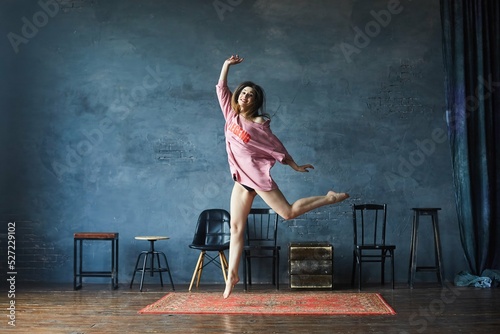 A girl in a pink sweater dances in a room with a loft design