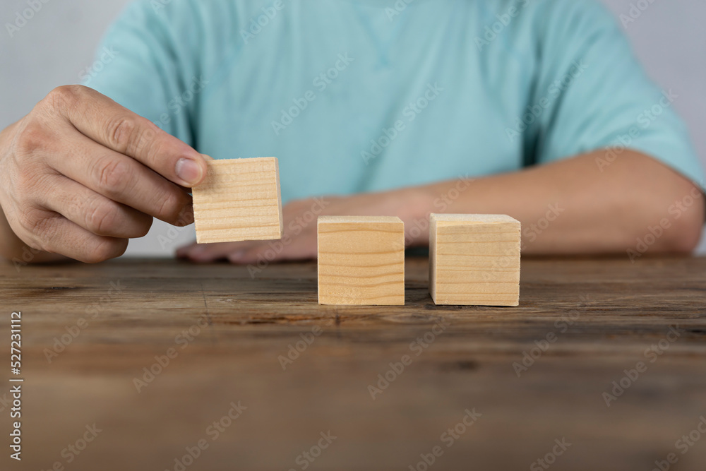 Close-up of three businessmen arranging wooden blocks Wooden toy blocks on a desk can be inserted with image text Close-up of three businessmen arranging wooden blocks Wooden toy blocks on a desk can be inserted with image text