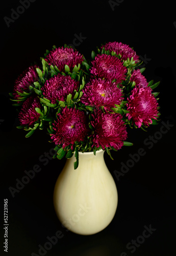 Dark red pionies in a vase on a black background. photo