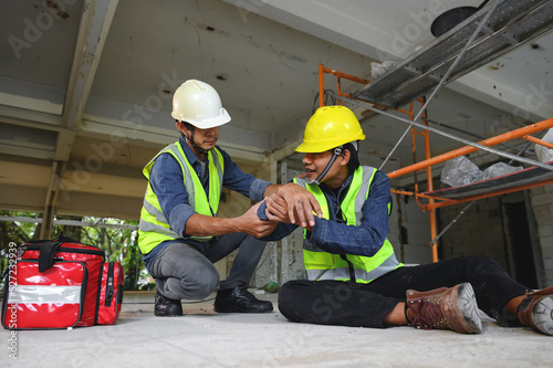 First aid support accident at work of builder worker on floor in the construction site. Elbow accident in work, Foreman help employee accident with first aid bag.