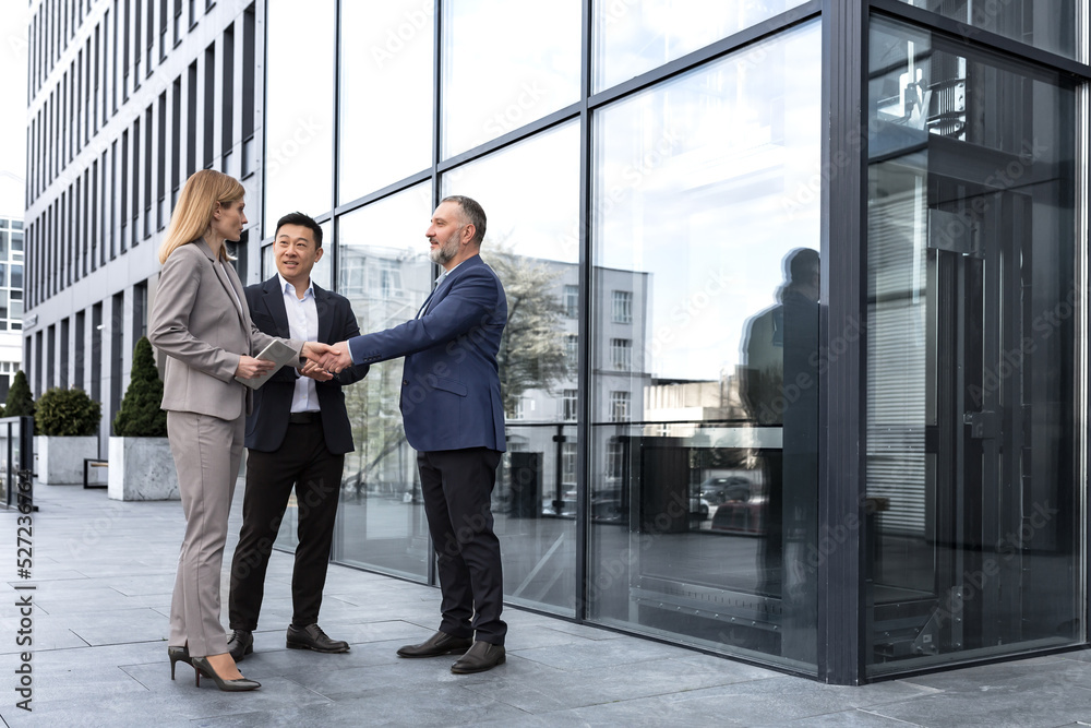 Meeting of three colleagues from outside the office building, experienced and mature IT specialists, greeting and shaking hands, business persons in business suits, diverse group of people Meeting of three colleagues from outside the office building, experienced and mature IT specialists, greeting and shaking hands, business persons in business suits, diverse group of people