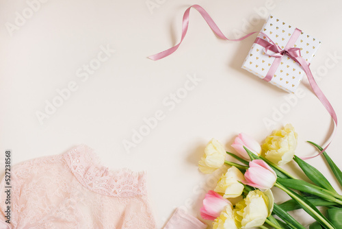 Women's clothing, gift box and tulip flowers. Minimalistic composition in pastel beige and pink tones. Top view, flat lay, copy space. The concept of a woman's birthday, fashion and blogging