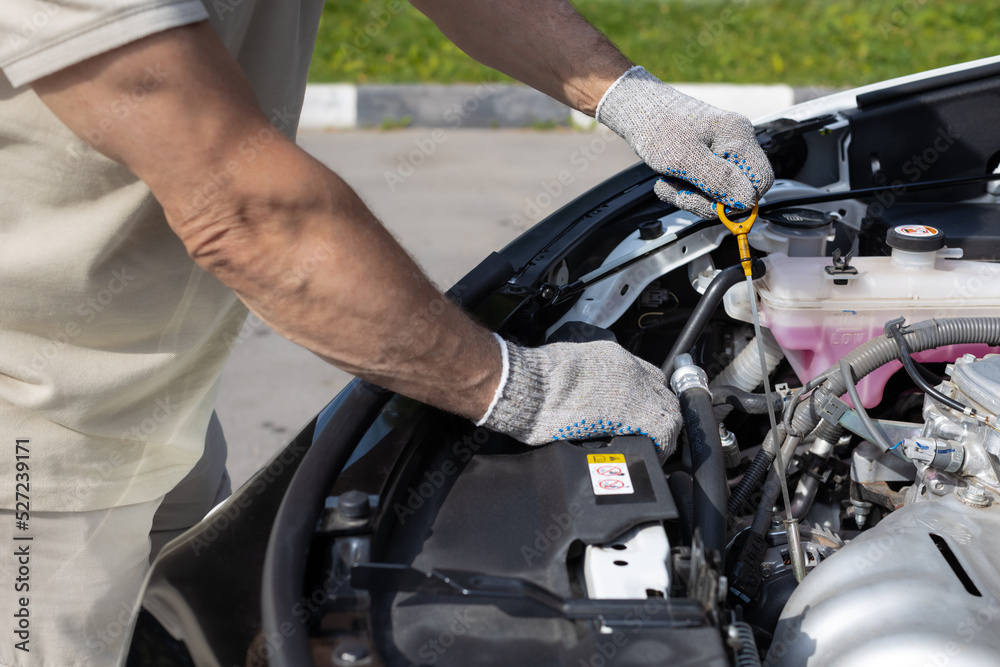 a man checks the oil level in a car engine a man checks the oil level in a car engine