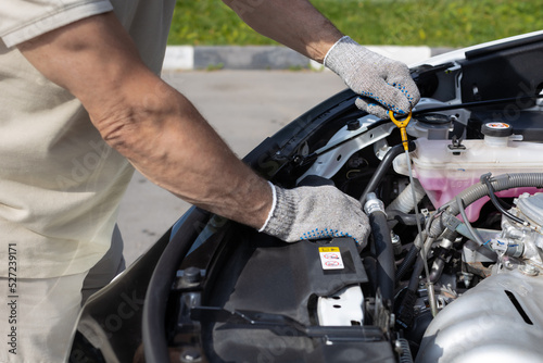 a man checks the oil level in a car engine