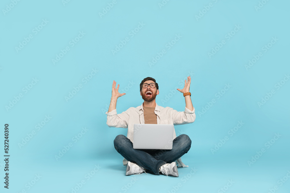 Emotional man with laptop on light blue background Emotional man with laptop on light blue background