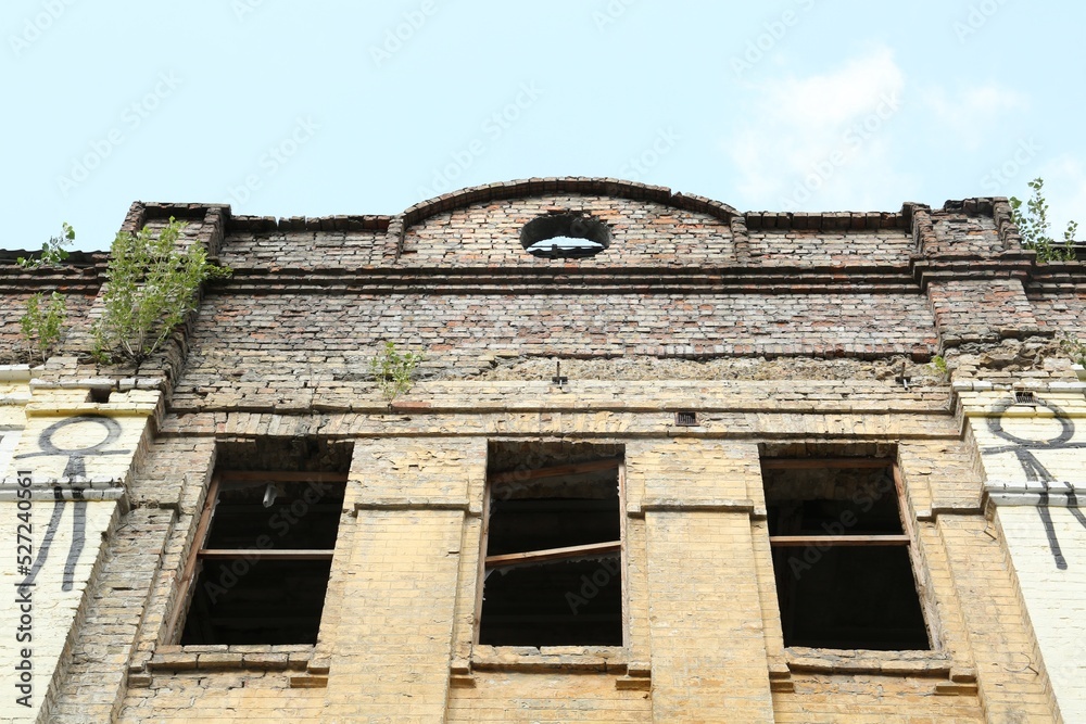Abandoned building with broken windows against blue sky, low angle view