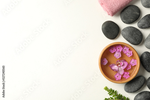 Flat lay composition with spa stones and flowers on white table. Space for text