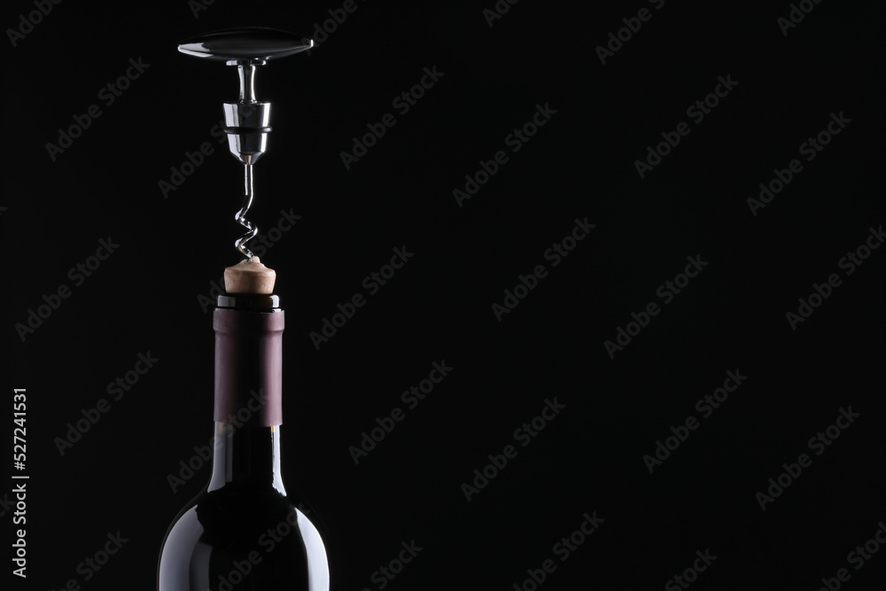 Opening wine bottle with corkscrew on dark background, closeup. Space for text - obrazy, fototapety, plakaty 