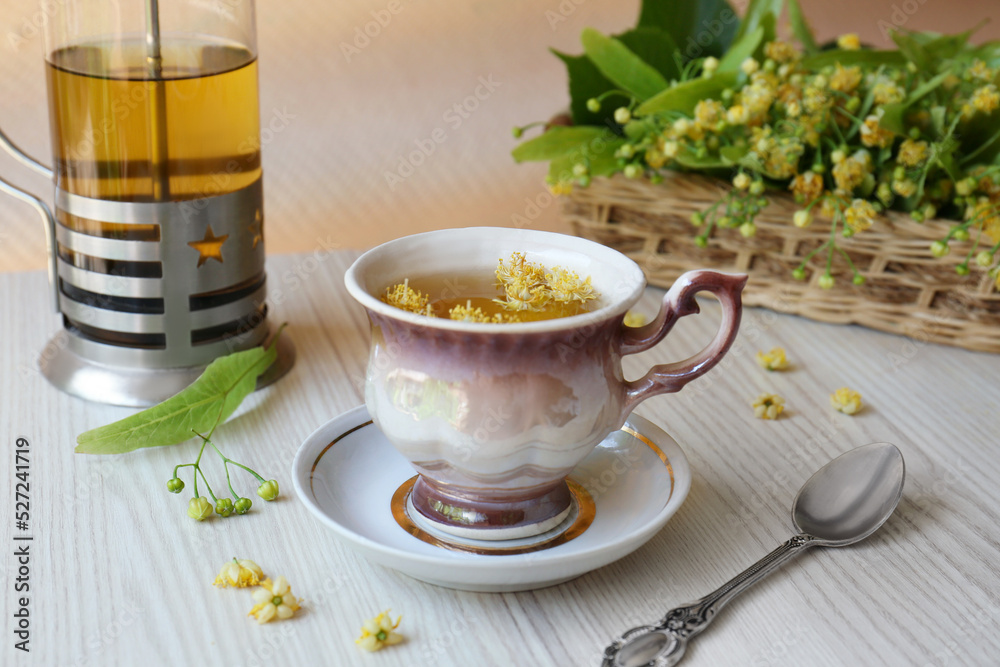 Aromatic tea with linden blossoms and spoon on white wooden table