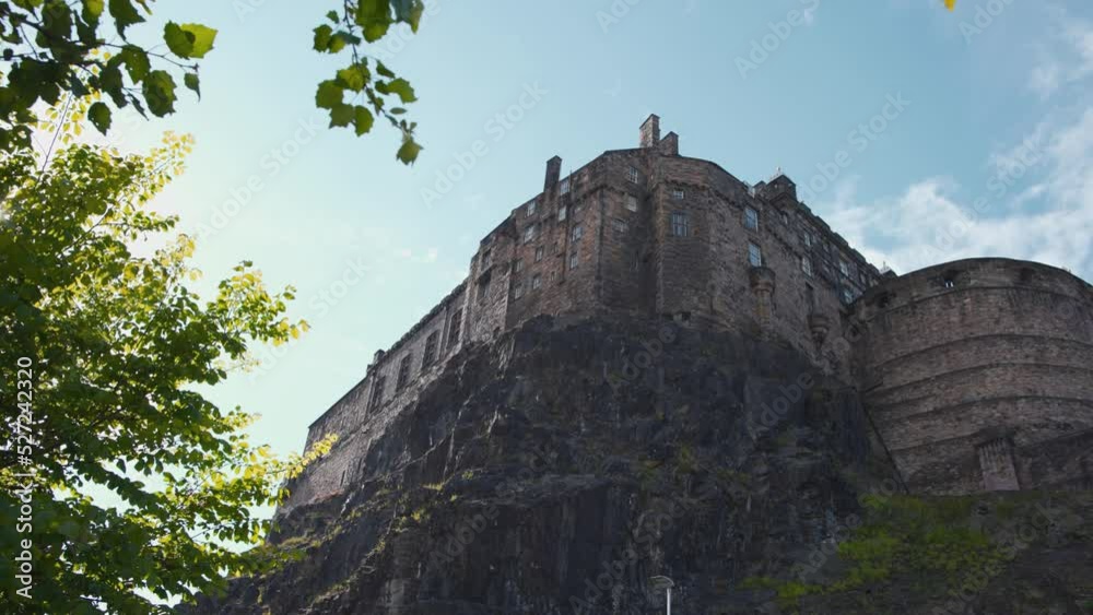 Low angle shot of Edinburgh castle on rock and sunlight through leaves.