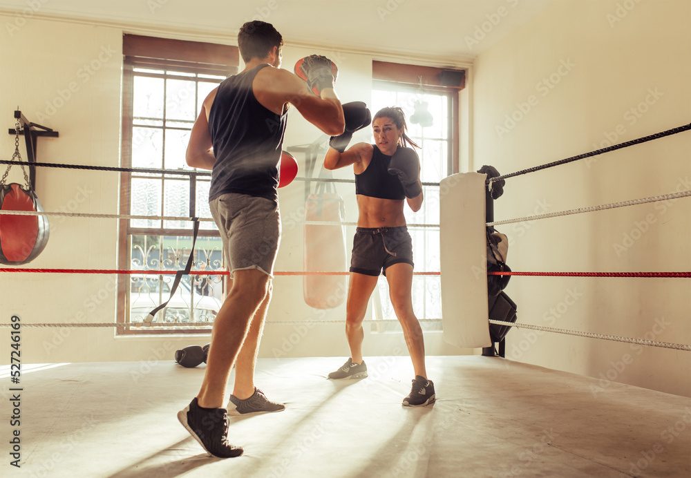 Fototapeta premium Trainer helping a female boxer with striking techniques