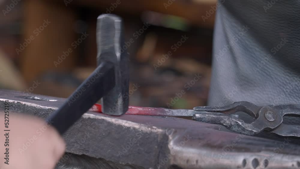 A close-up of the hands and hammer of a blacksmith and his assistant forging a small piece of metal. A close-up of the hands and hammer of a blacksmith and his assistant forging a small piece of metal.