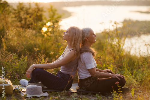 portrait of a smiling senior woman with an adult daughter relaxed outdoors at sunset. copy space. Slow life. Enjoying the little things. spends time in nature in summer