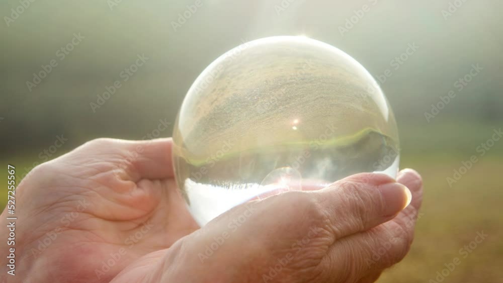 Cinemagraph of old womans hand holding a shiny glass ball
