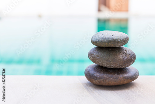 Zen stone stack on swimming pool edge, outdoor day light
