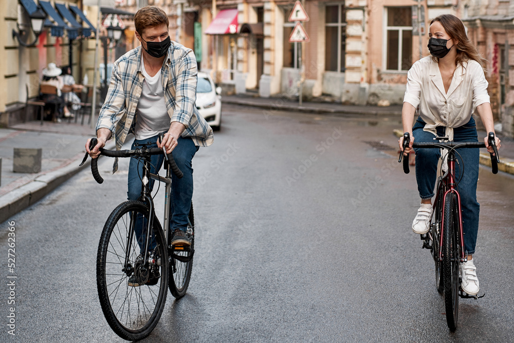 Obraz premium Caucasian couple wear medical masks ride bicycles
