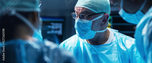 Photos Diverse team of professional medical surgeons perform surgery in the operating room using high-tech equipment