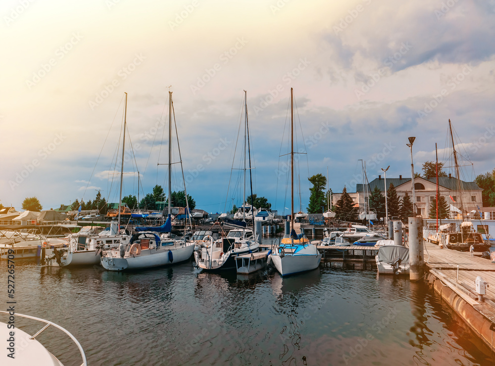 Boats and sailboats moored to a pier in a yacht marina.