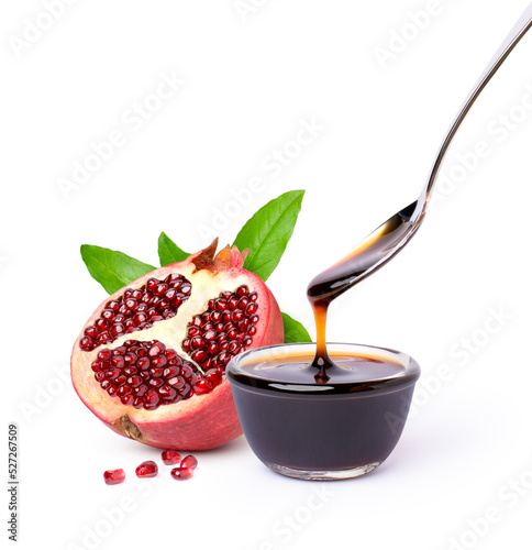 Pomegranate fruit with pomegranate molasses in glass bowl with spoon isolated on white background. photo