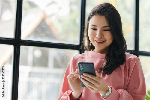 Asian woman working in a startup company, she is using the phone. run by a young, talented woman. The management concept runs the company of female leaders to grow the company.