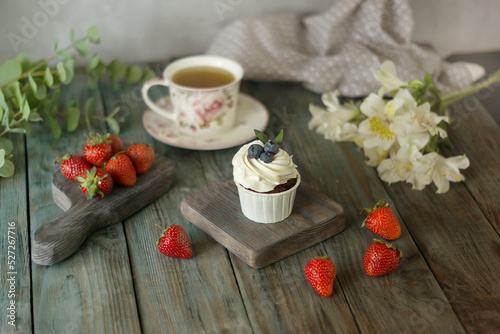 Vanilla cupcake with fruits, hot cup of tea on wooden table background, top view, copy space. Seasonal, morning Sunday breakfast and rest.