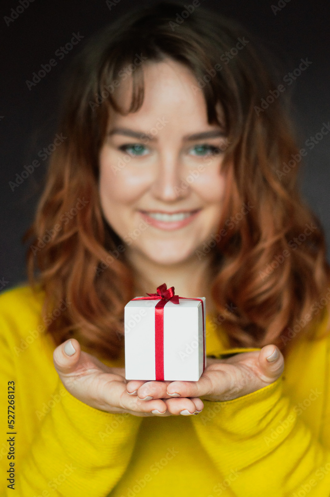 a girl holding a box with a gift in her hands smiles a surprise for a holiday celebration meeting what to give money decorations a girl holding a box with a gift in her hands smiles a surprise for a holiday celebration meeting what to give money decorations