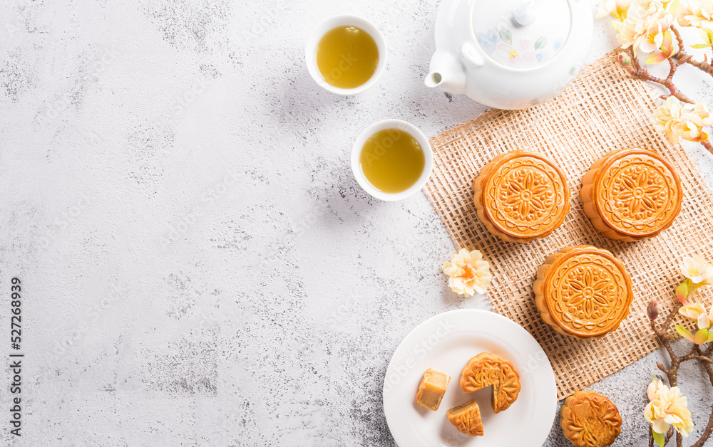 Chinese Mid-Autumn Festival concept made from mooncakes, tea and plum blossom on white stone background. Chinese Mid-Autumn Festival concept made from mooncakes, tea and plum blossom on white stone background.