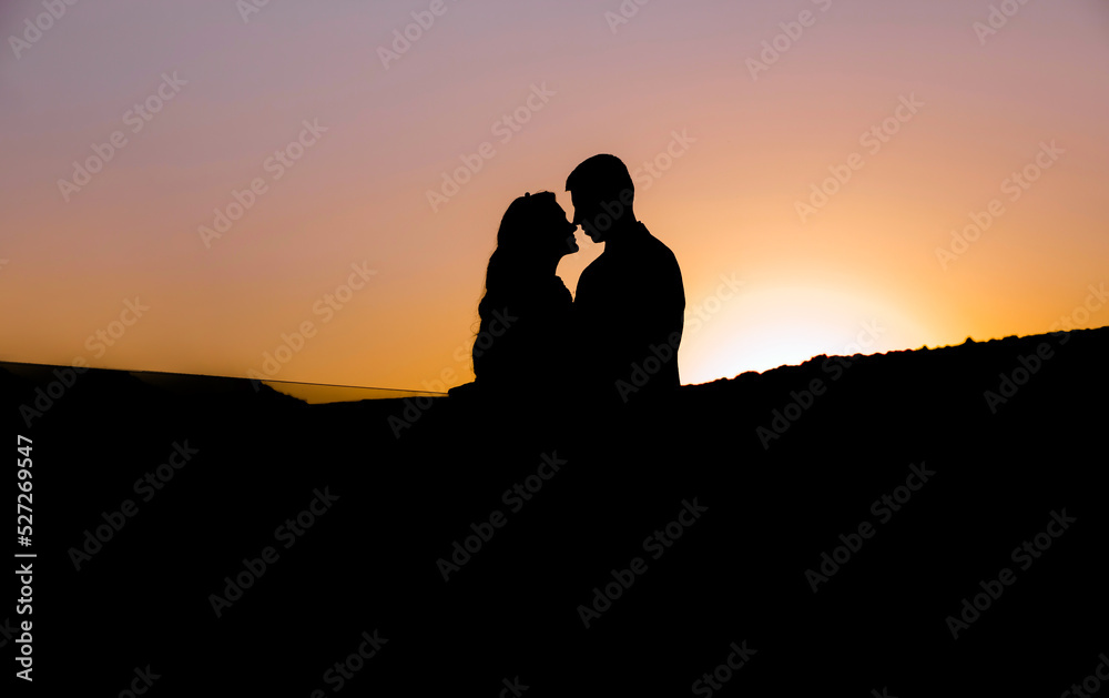 Wedding silhouette couple of lovers kissing on sunset with evening sky background
