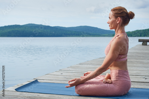 Mature woman in pink sportswear practices yoga. The concept of a healthy lifestyle. copy space for advertising