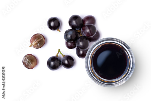 Black grapes and grape molasses in glass bowl isolated on white background, Top view, flat lay. photo