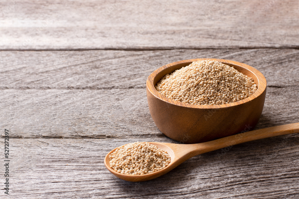 Quinoa seeds (Chenopodium) in wooden bowl and spoon isolated on wooden table background. Quinoa seeds (Chenopodium) in wooden bowl and spoon isolated on wooden table background.