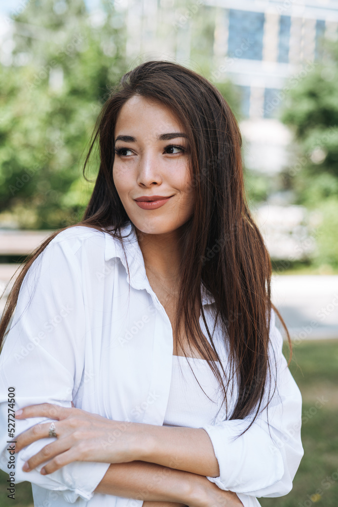 Portrait of young asian woman student with long hair in city park