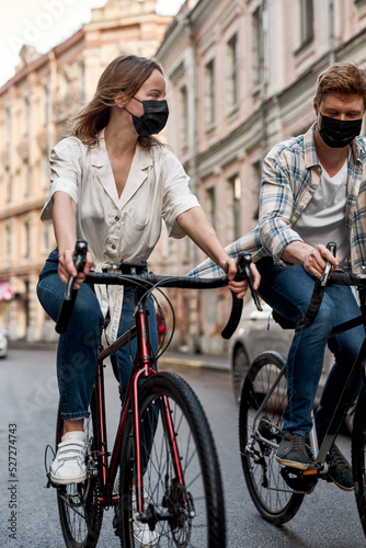 Man and girl wearing medical masks riding bicycles
