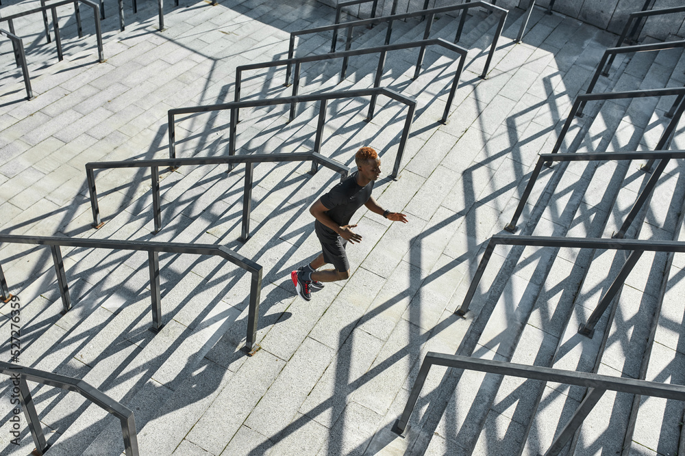 Top of young black sportsman running on staircase