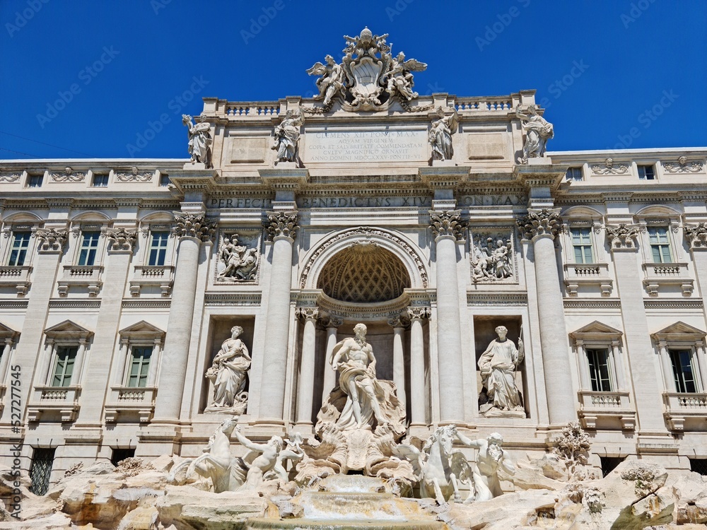 Scenic cityscape with Trevi fountain in the old city in the morning sun lights. Beautiful view of marble sculptures on a sunny day. People like take a photo near Italian landmarks. Famous palace decor