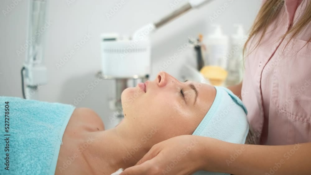 Beautician therapist applying face treatment in beauty salon to young woman. Beautician therapist applying face treatment in beauty salon to young woman.
