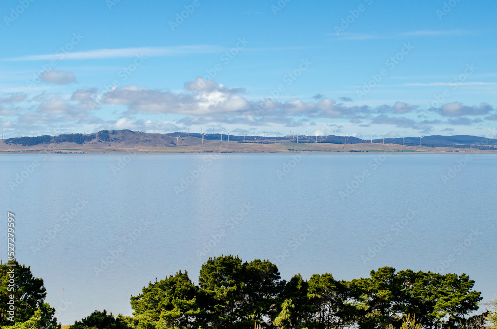 Beautiful view of Lake George with blue water against the sky with a wind farm in the distance. Background texture of Australian natural landscape of the inland endorheic freshwater lake.