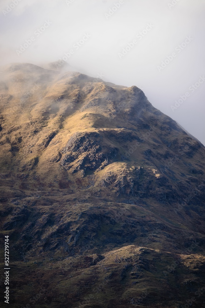 Vertical shot of mountains in early morning fog and clouds in the Scottish Highlands - obrazy, fototapety, plakaty 