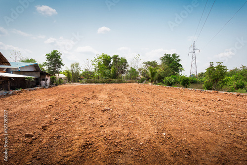 Empty dry cracked swamp reclamation soil, land plot for housing construction project with car tire print in rural area and beautiful blue sky with fresh air Land for sales landscape concept.