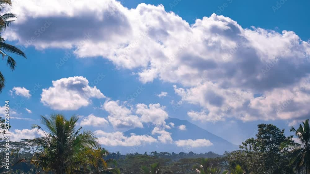 Timelapse of clouds moving from wind on sunny day with a mountain on background. Palm trees, tropical area