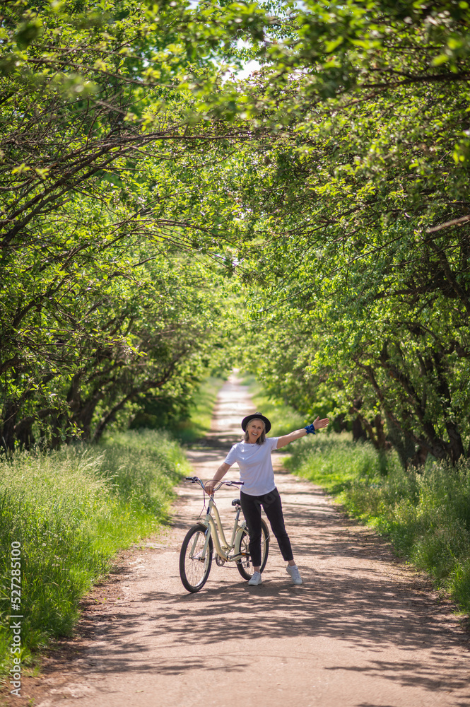 A woman with a bike on a road in the park