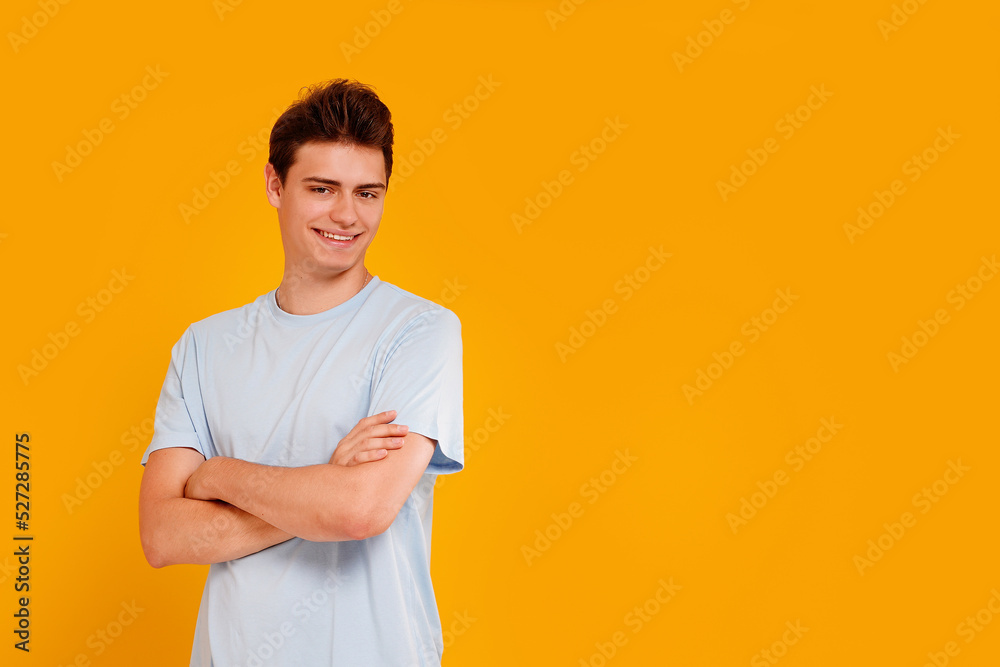 Fashionable young student boy standing on the yellow studio background, looking and smiling at the camera. Fashionable young student boy standing on the yellow studio background, looking and smiling at the camera.