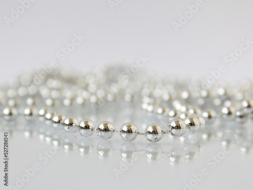 Silver pearl decoration beads close-up on white mirror background