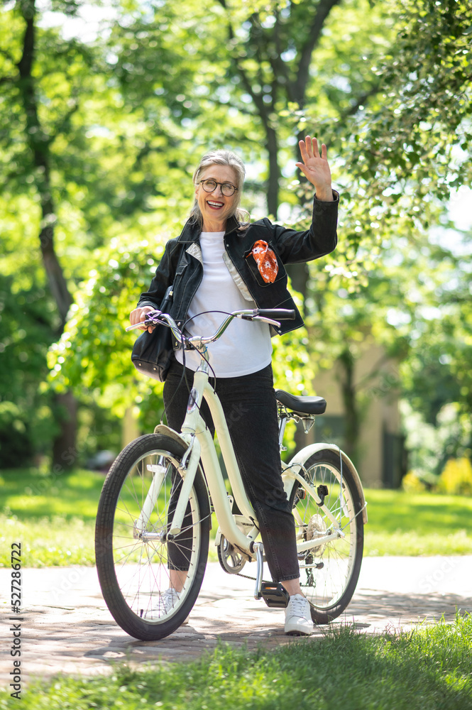 Obraz premium Mature woman on a bike in a summer park