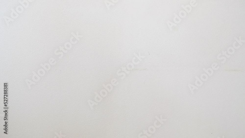 a hand paints a white wall with a construction paint roller